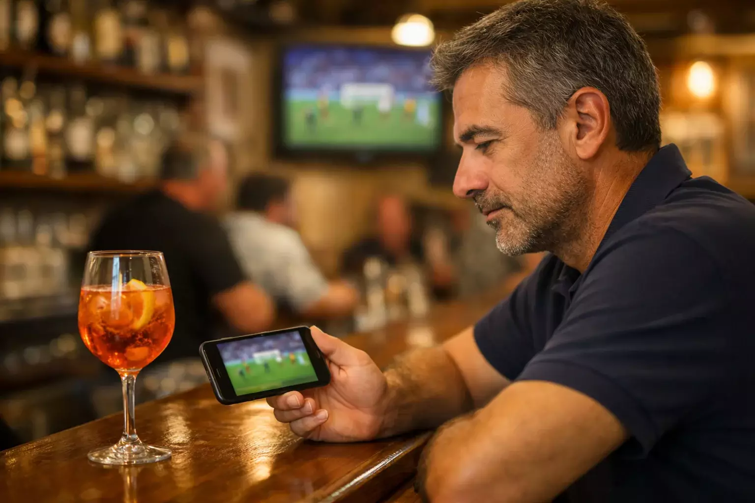 Tifoso segue una partita di calcio sullo smartphone seduto al bar